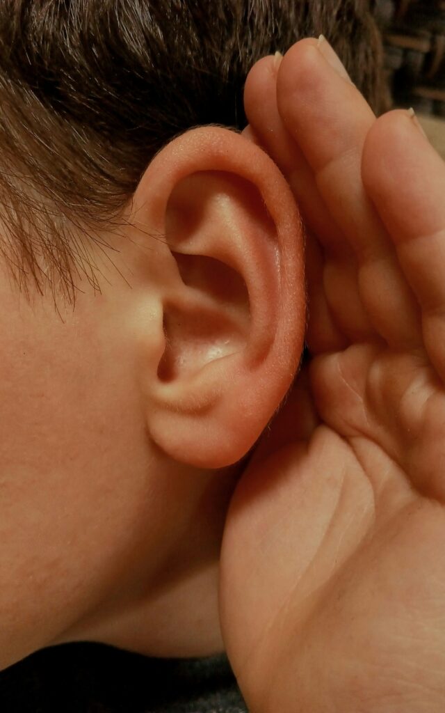 A hand cupped behind an ear, straining to hear