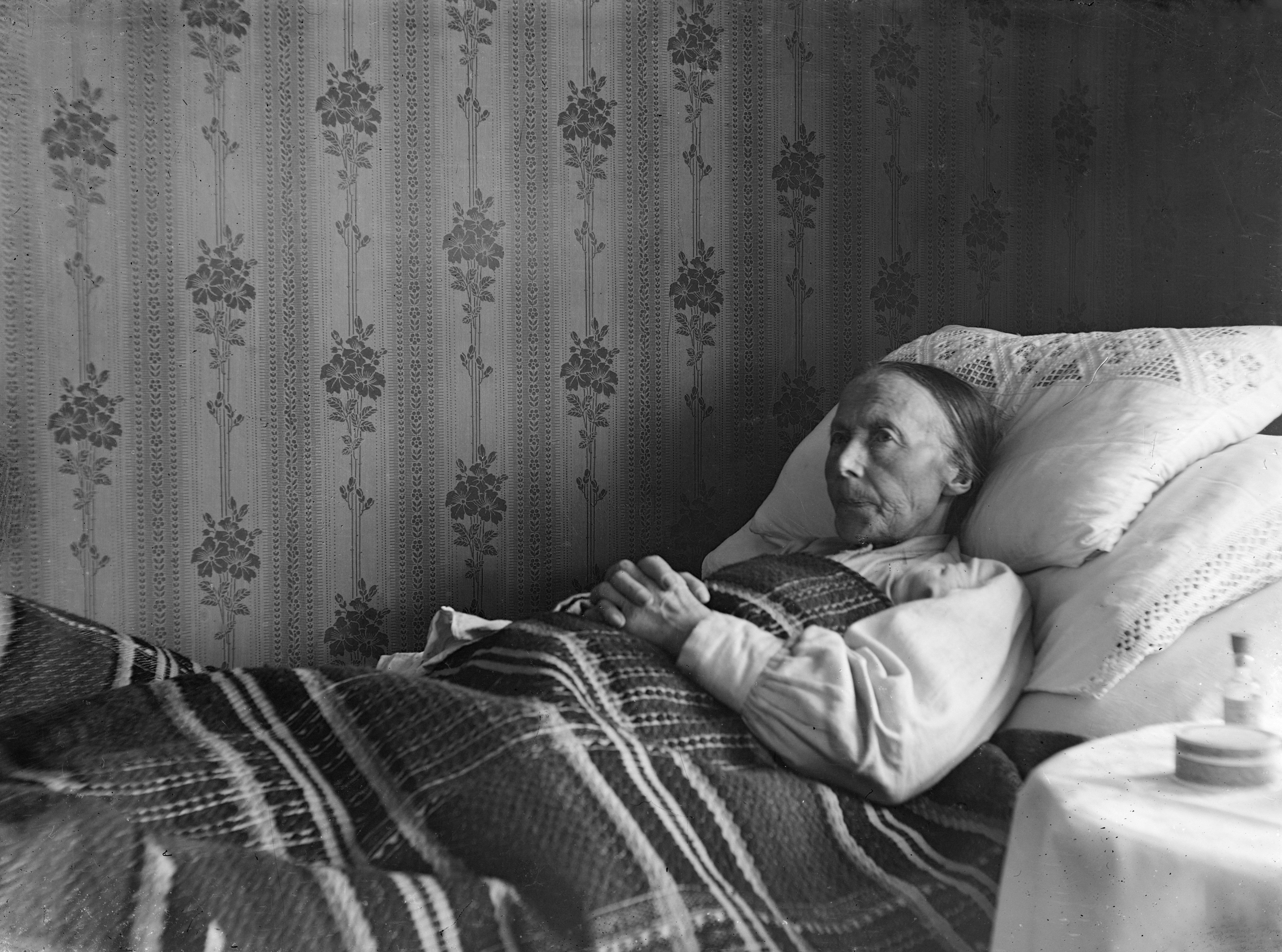 An older woman lying awake in bed, eyes open, looking at the ceiling
