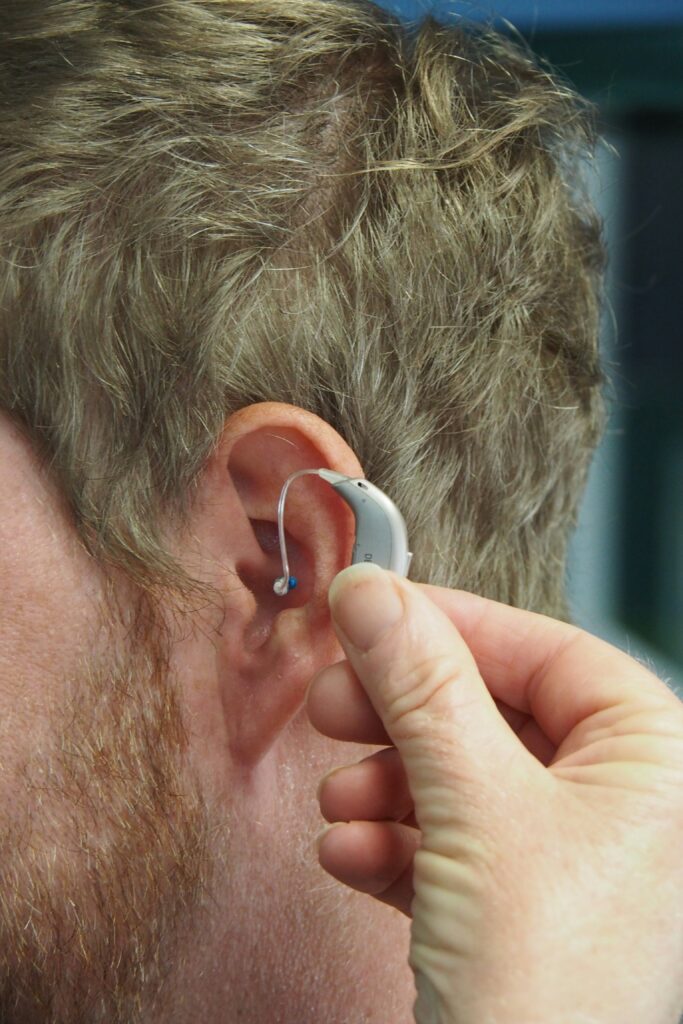 A man fitting a hearing aid behind his ear