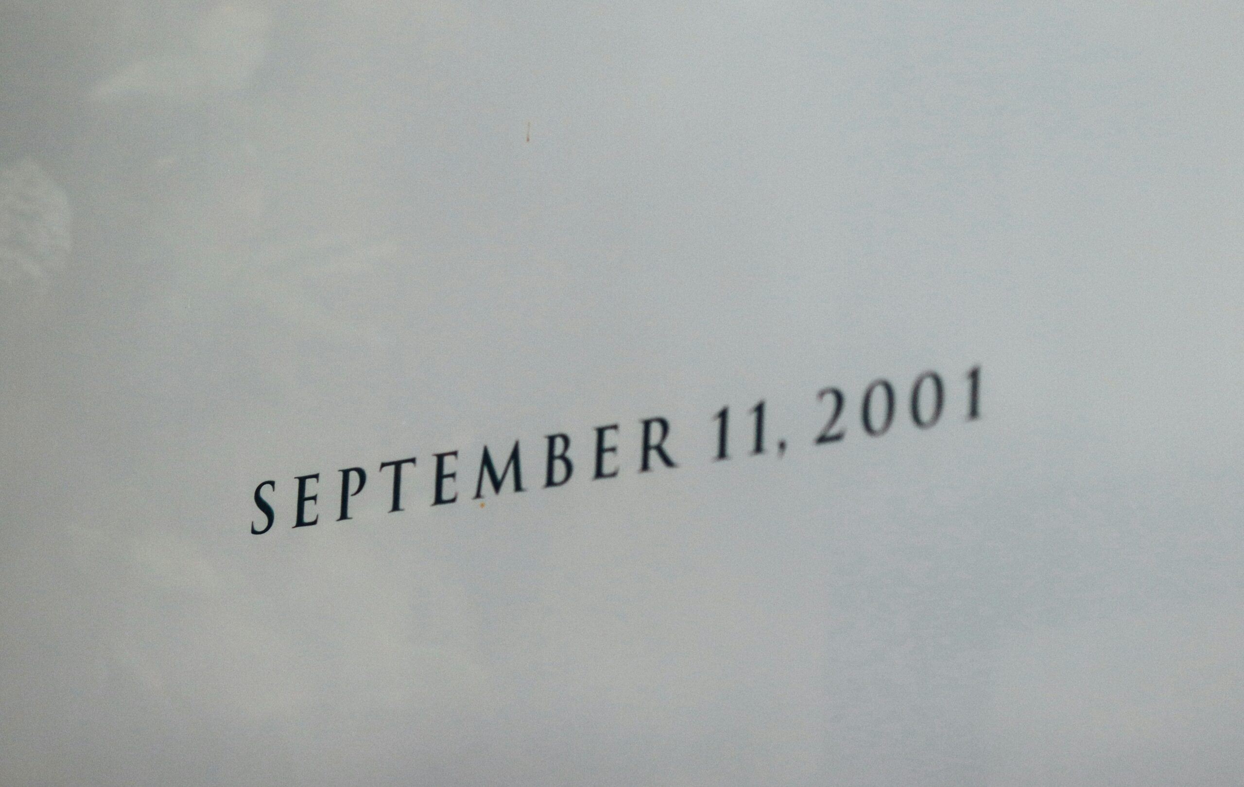 The words SEPTEMBER 11, 2001 engraved in pale stone, photographed close and with shallow depth of field.
