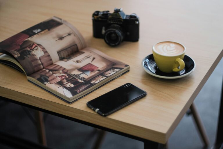 An open photo album, a camera and a phone on a table