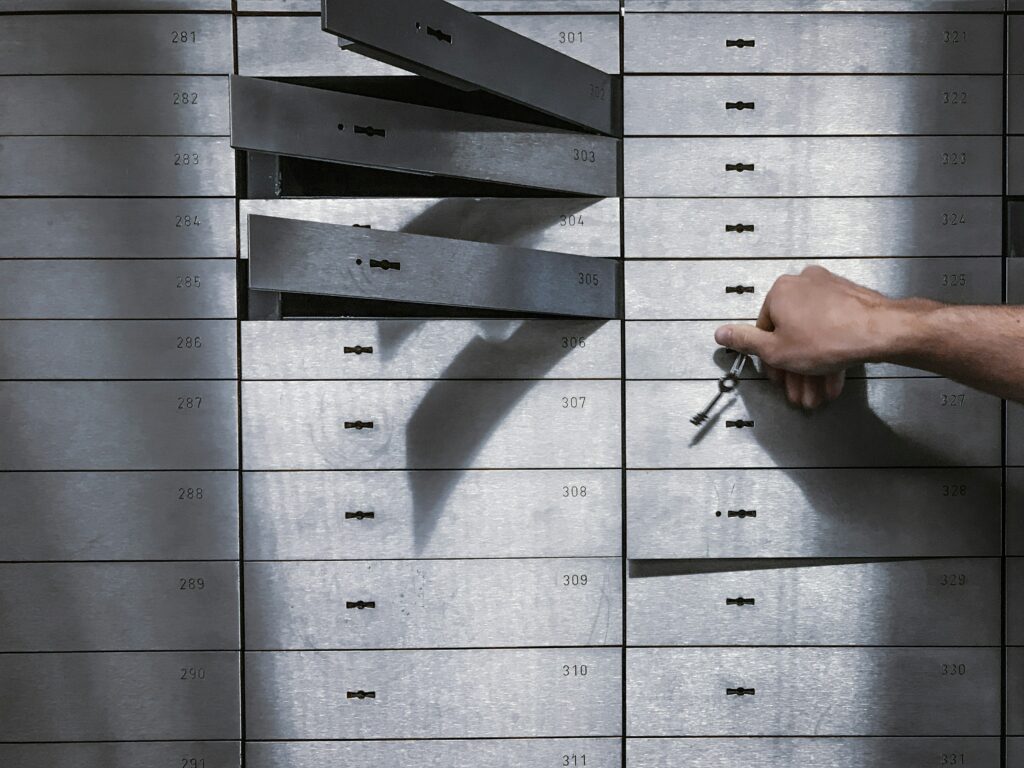 A hand opening a safe deposit box in a bank vault