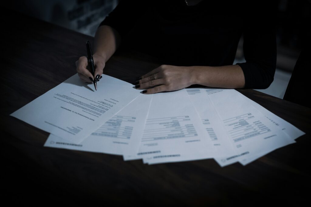 Hands signing legal documents spread across a table