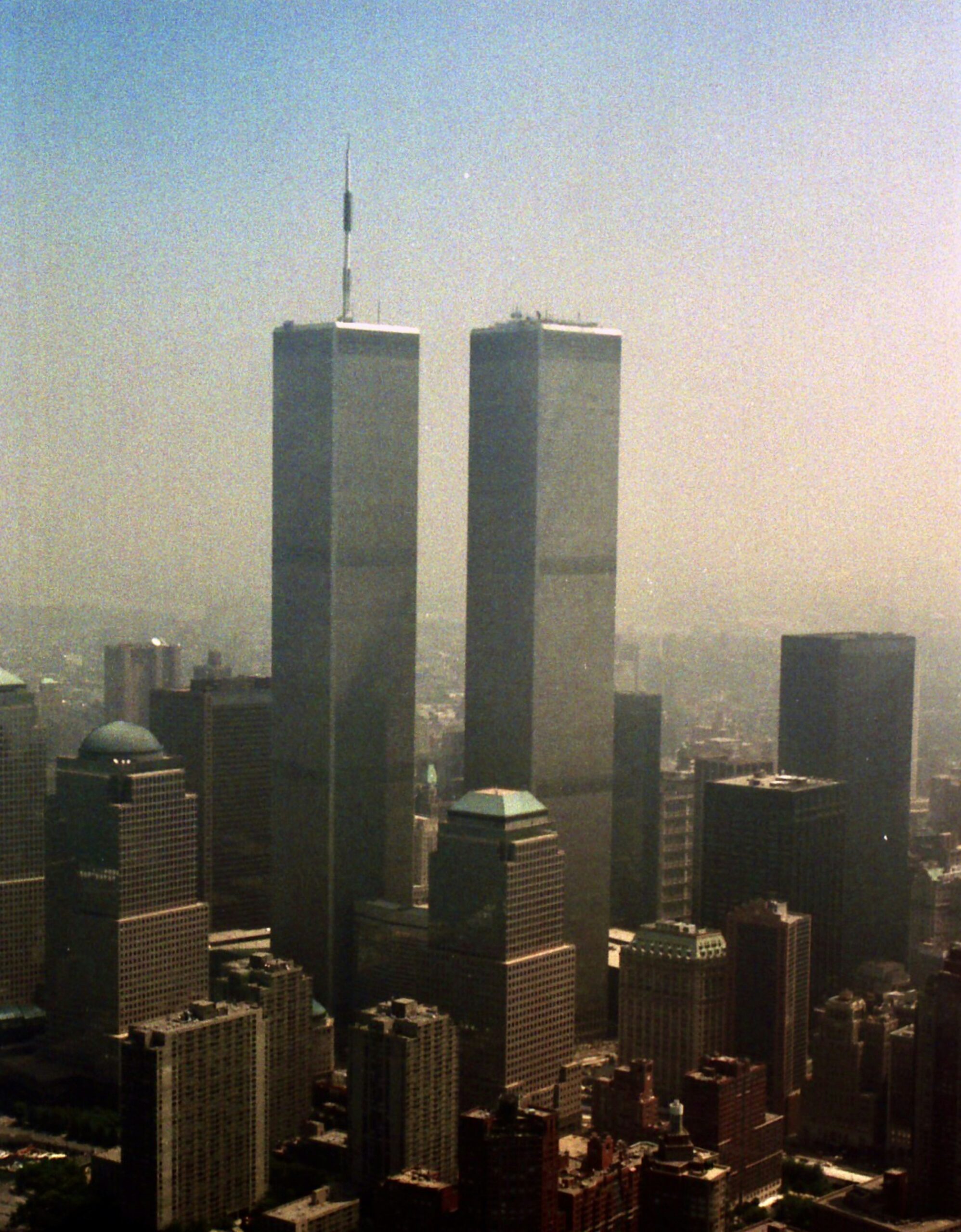 The Twin Towers standing against a hazy daylight sky above the lower Manhattan skyline.