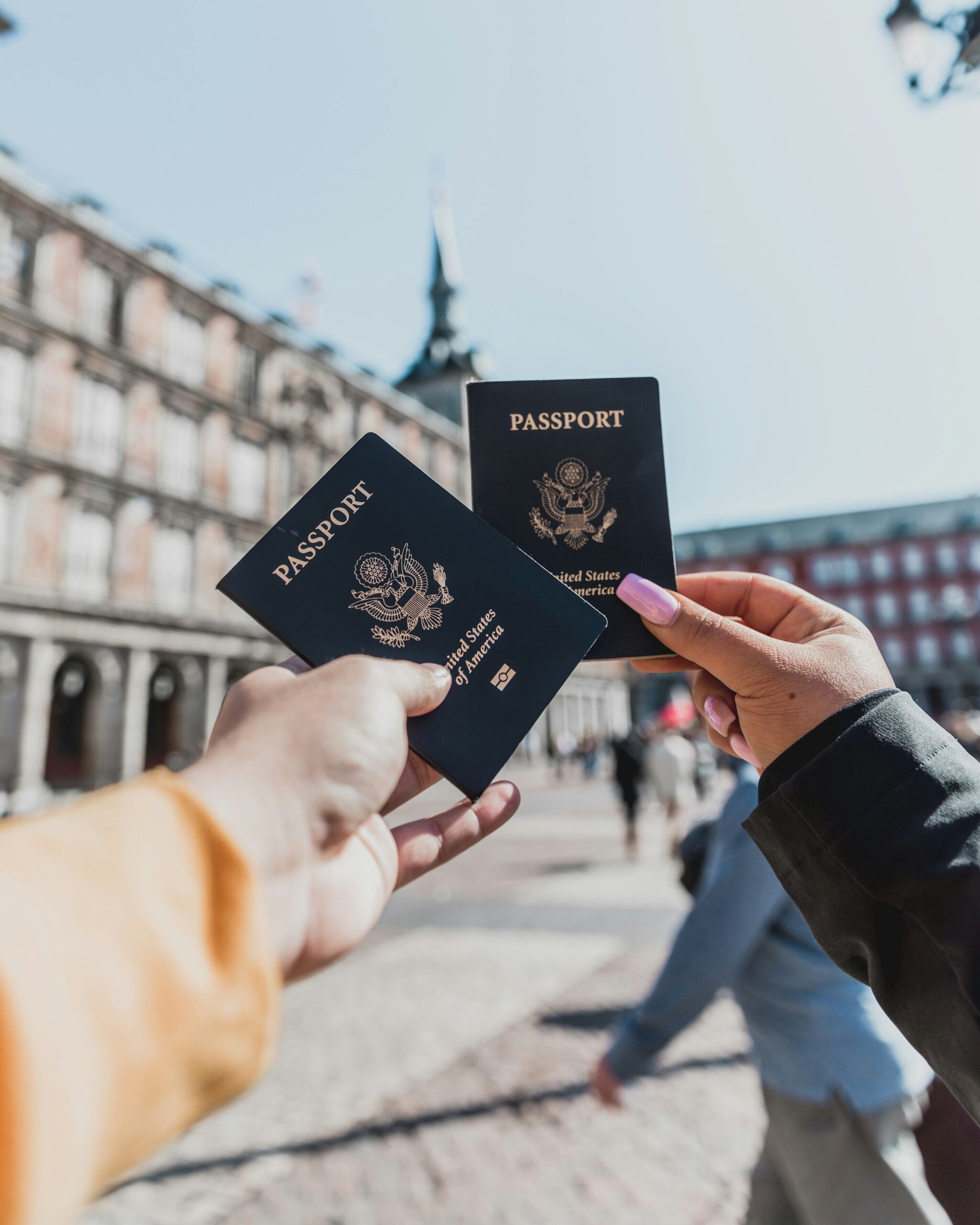 Two travelers holding United States passports in a European plaza